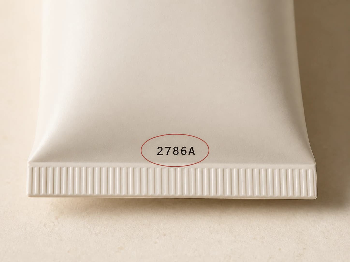 Batch code stamped on the crimped end of a cosmetic tube